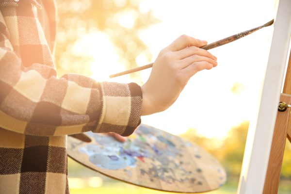 Close up view of female artist painting picture outdoors Close up view of female artist painting picture outdoors